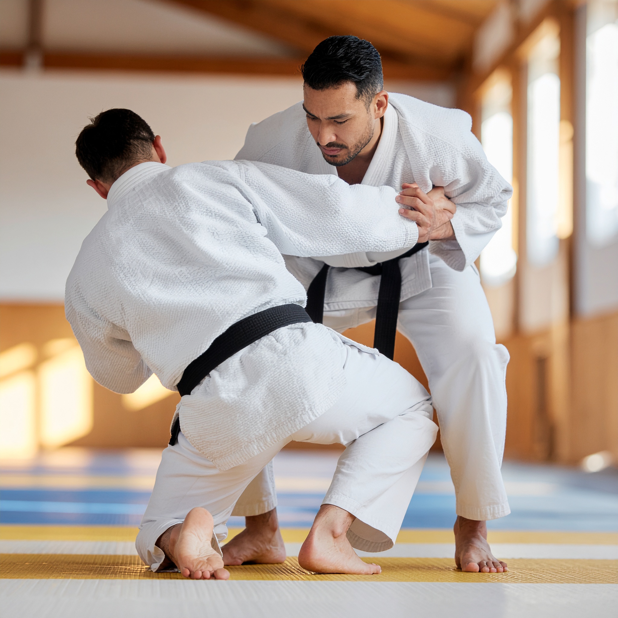 Adult black belt judo coach training a young student at Darfight in Brooklyn dojo.